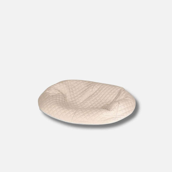 Beige, ovaalinmuotoinen allergivennlig hundeseng, jossa on quiltet topptrekk, jossa on hieman uurrettu pinta ja joka on kuvattu yksivärisellä valkoisella pohjalla.