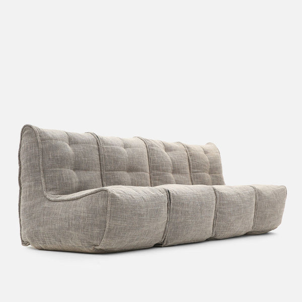 Moderni, matalaprofiilinen design-sohva beige, jossa on tuftattu selkänoja ja istuin, pehmeät, pyöristetyt reunat ja kuvioitu kangasverhoilu - täydellinen tyylikkäänä hjemmekino-sohvana valkoista taustaa vasten.
