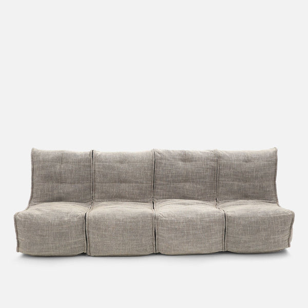 Moderni nelipaikkainen design-sohva, jossa on vaaleanharmaa, kuvioitu kangasverhoilu. Mallissa on pehmeät, pehmustetut istuimet ja selkänojat, joissa on näkyviä saumoja, valkoista taustaa vasten.