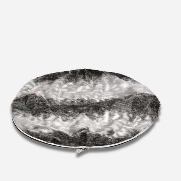 Pyöreä, litteä hundeseng, jossa on luksuriøs pelstopp ja pehmeä fuskepelstrekk harmaan, valkoisen ja mustan sävyissä. Reunaa pitkin kulkee näkyvä vetoketju, joka on kuvattu yksivärisellä valkoisella pohjalla.