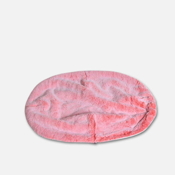 Pehmeä, ovaalin muotoinen hundeseng peitetty pörröinen vaaleanpunainen fuskepelstrekk, joka tarjoaa ripaus luksuriøs pelstopp mukavuutta, sijoitettu tavallinen valkoinen tausta.